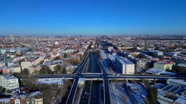 Berlin cityscape from above showing a complex road network, traffic flow, railway lines, and buildings during a winter day. Gorgeous aerial view static panorama hovering drone