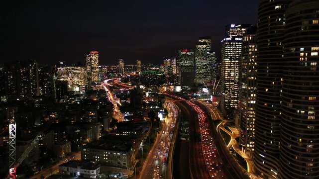 Aerial view of the city's illuminated skyscrapers and a busy highway, a vibrant scene of urban life at night, Tel Aviv-Yafo, Tel Aviv District, Israel.