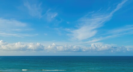 Peaceful view of a bright blue sky with soft white clouds over the endless ocean