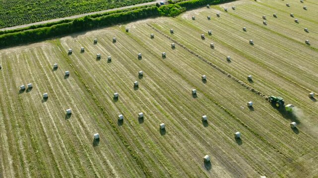 Aerial view of a round baler working in a hay bale field. Drone's turnaround on a baler making a bale. Hay Baling Process.