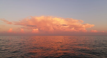 Fototapeta premium Peaceful sunset scene featuring glowing salmon pink clouds over ocean