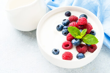 Yogurt with fresh berries in white bowl.