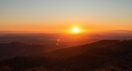 Obraz premium Sunset glowing over rolling hills with layered horizons and copy space for captions
