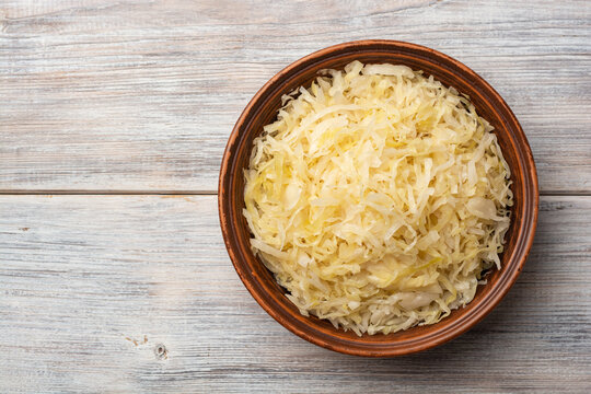 Homemade sauerkraut in bowl on wooden background.