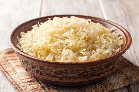 Homemade sauerkraut in bowl on wooden background.