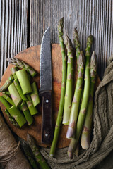 Fresh green asparagus arranged with fabric napkin on wooden surface. Raw seasonal vegetables in...