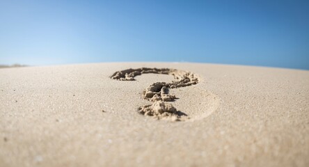 Obraz premium A question mark manually written in sand under bright natural sunlight