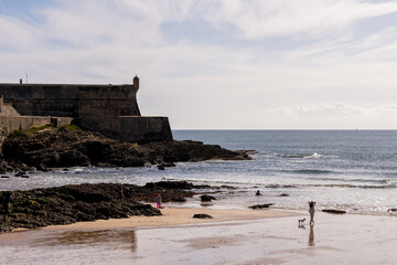 Reflective wet sand beach with visitors in Cascais
