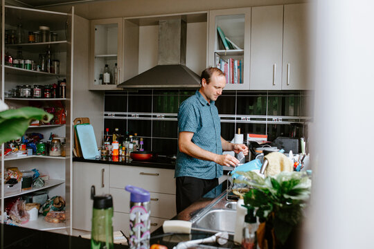 Caucasian man doing dishes in the kitchen sink