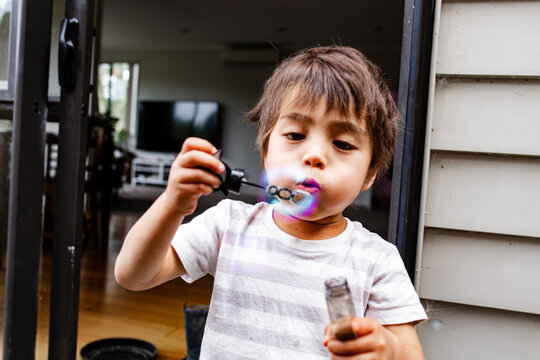 Young boy blowing bubbles with a bubble wand