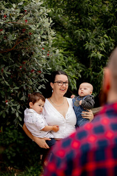 Happy mum holding both sons in the backyard