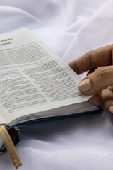 Hand Turning Bible Page on White Fabric
