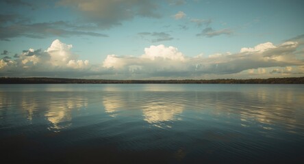 Fototapeta premium Natural landscape with a calm lake reflecting cumulus clouds forming a serene horizon