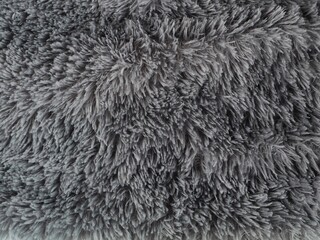 Top view of grey faux fur texture background with long hair fibers. Ideal for fashion, interior design, or winter-themed backgrounds © Eka