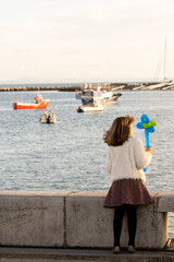 Child holding balloon toy overlooking fishing harbor
