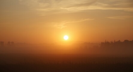 Brilliant early light featuring a large sun sinking beneath a somber background