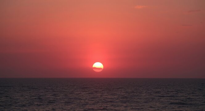 Soft pink sunset glow accompanied by spectacular sun rays on ocean