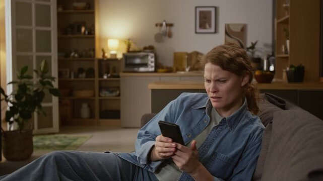 Medium shot of woman relaxing with smartphone on couch at home, seeing money withdrawal alerts, reacting with confusion and dismay, frantically logging into banking app, seeing empty savings account