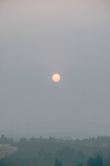 Fototapeta premium Orange sun partially obscured by thick wildfire smoke in southern Chile.