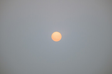 Fototapeta premium Orange sun partially obscured by thick wildfire smoke in southern Chile.