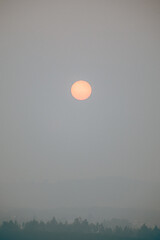Fototapeta premium Orange sun partially obscured by thick wildfire smoke in southern Chile.