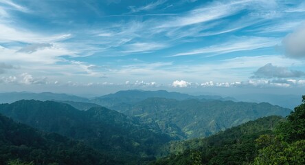 Fototapeta premium Wide natural view of rich green mountain heights with scattered cloud cover and a clear blue sky plus copy space