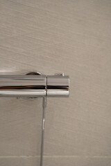 Chrome shower mixer on a clean tiled wall enhancing bathroom design with its sleek, metallic finish, integrating modern plumbing for daily hygiene and comfort