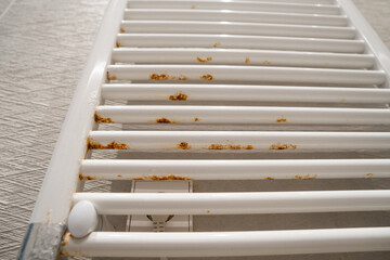 White bathroom towel warmer radiator showing signs of extensive rust accumulation and paint damage, illustrating metal corrosion and need for maintenance