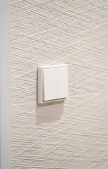 White double light switch on a textured wallpapered wall, representing concepts of electricity, home automation, comfort, modern living, and essential household controls