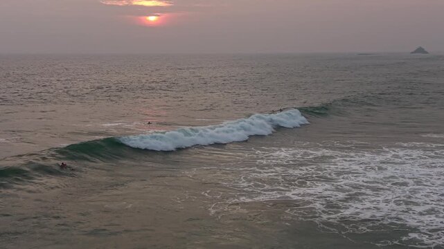 Beautiful sunset surf session at Naomi Beach. Surfers floating and catching waves in warm golden light, calm ocean, and scenic tropical horizon. Ideal footage for vacation, freedom, extreme sports, an