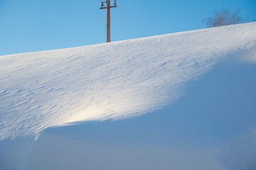 snow drifts on the roof of the house, dangerously overhanging boulders, snow removal with a shovel