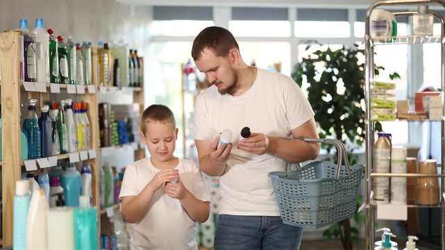  Young man with his son buyers chooses deodorant in household chemicals store