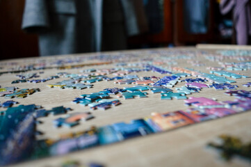 Fototapeta premium Jigsaw puzzle pieces on table, close up. Rising trend of analog hobbies, offline leisure, mindfulness activity, slow living, stress relief, cozy home entertainment and digital detox concept.