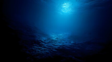 Fototapeta premium Sunlight streams into the deep blue ocean depths illuminating the textured seabed below