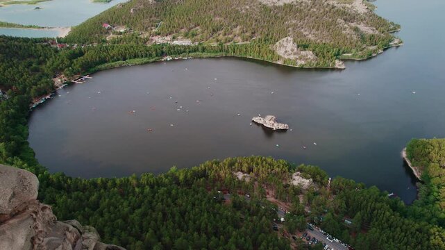 Beautiful landscape of tranquil lake with boat, forests and rocky mountains. Aerial view National nature park Burabay, Kazakhstan.