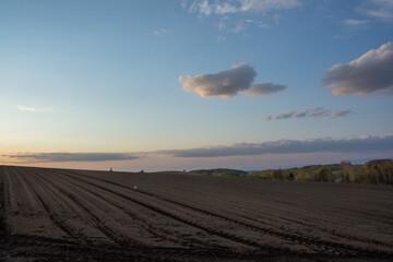 春の晴れた夕暮れの空と耕し終わった畑