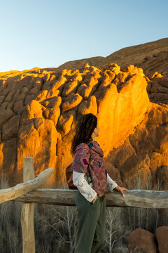 Woman with a patterned scarf looks at the rock formations, Monkey fingers, at sunset. Dades gorges,Monkey fingers,Marrakech,Morocco