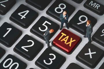 Business tax concept with miniature businessmen standing on calculator and red tax button. Corporate taxation, financial planning, accounting strategy and fiscal responsibility theme.