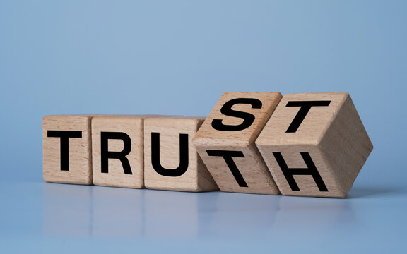 Trust and truth concept with wooden letter blocks flipping on blue background. Business integrity, honesty, transparency and credibility symbol represent ethical leadership and strong mindset.