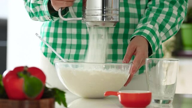 Woman sift a flour in a bowl,make a dough