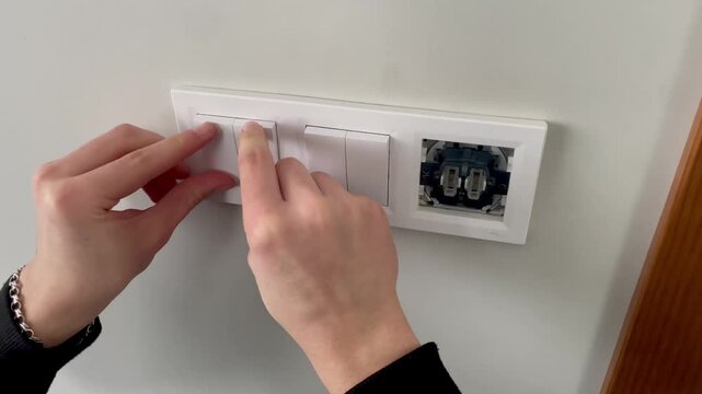 Close-up of hands installing a white decorative frame and plastic buttons on a triple light switch, final assembly.