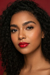 Fototapeta premium Close-up portrait of a beautiful woman with curly dark hair and vibrant red lipstick.