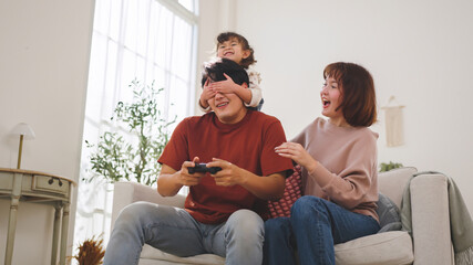 Happy Asian family playing console game together at home