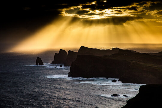 Dramatic coastline and rocks at sunset in Madeira Portugal with sun rays shining through clouds