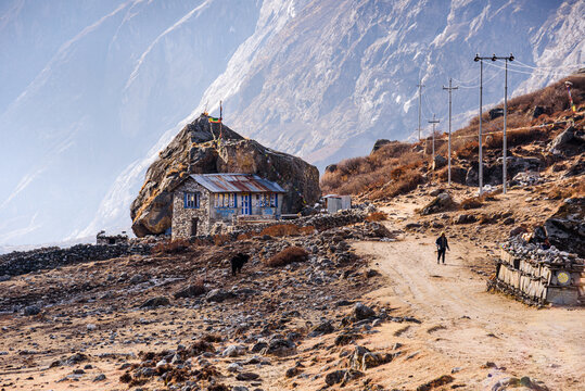 Small stone teahouse called 'Hard Rock' Cafe on mountain trail above Langtang Valley with dramatic Himalayan cliffs