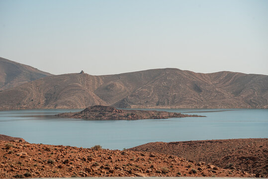 Still waters of Barrage Al-Hassan Addakhil in Parc National Al Hassan Addakhil near Errachidia, surrounded by arid red hills and rugged mountain slopes