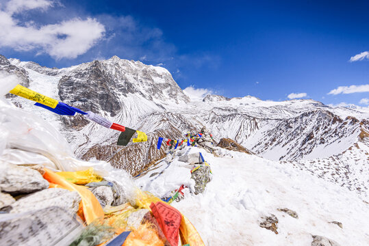 Colorful prayer flags draped along the snow-covered summit of Kyanjin Ri with Langtang lirung slopes in the background, Langtang Valley