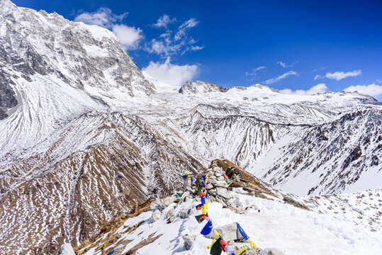 High-altitude view north from Kyanjin Ri summit with prayer flags and dramatic snow-covered ridges above Ubra and Kimshung, Nepal