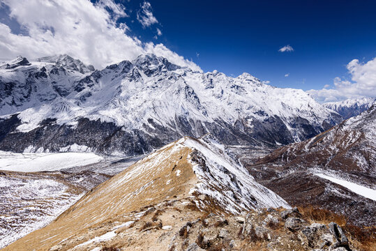 Narrow snow-covered ridge trail ascending toward Kyanjin Ri with panoramic views of Langtang Himal and Scout Peak, Langtang National Park, Nepal