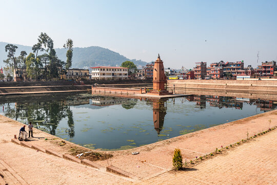 Stone steps surrounding the Siddha Pokhari pond in Bhaktapur, reflecting temple structures and distant hills